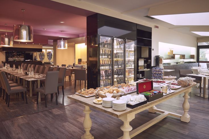 Ristorante moderno con un'area buffet e una selezione di vini, adatto per la colazione. Atmosfera accogliente.