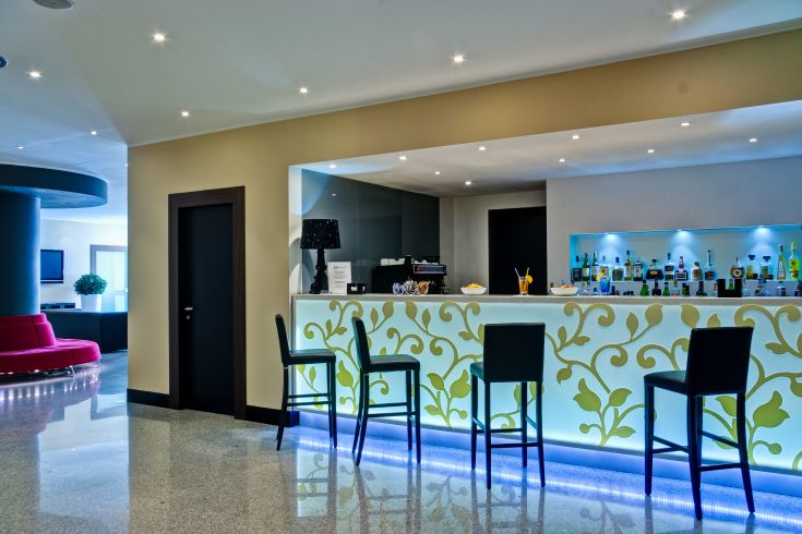 Bar situato all'interno di un hotel, caratterizzato da un'illuminazione contemporanea e un ambiente confortevole.