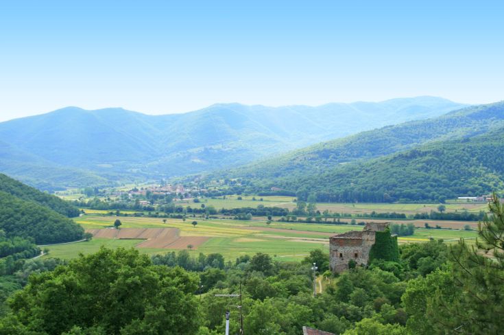 Ein ruhiger Blick auf das umbrische Tal mit sanften Hügeln und Überresten antiker Strukturen.