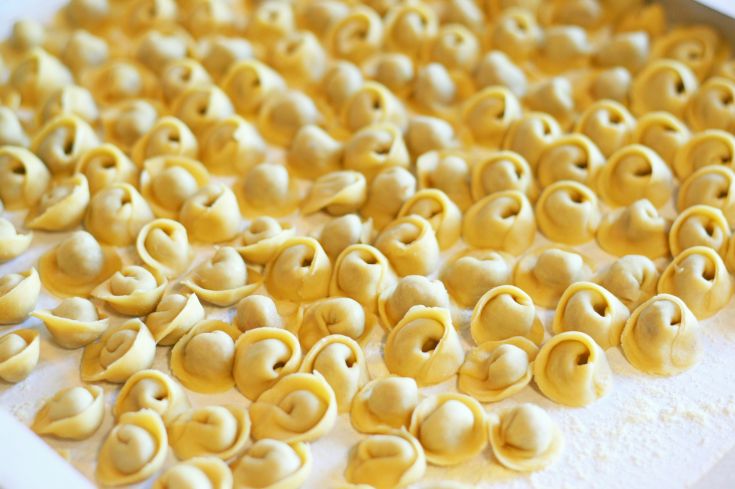 Frische Tortelli auf einer bemehlten Oberfläche, bereit zum Kochen.
