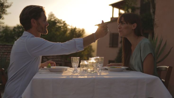 Zwei Personen essen im Freien in einer natürlichen Umgebung bei Sonnenuntergang.