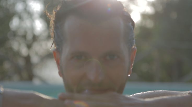 Ein ruhiger Mann in einem Pool, mit warmem Licht, das eine friedliche Atmosphäre schafft.