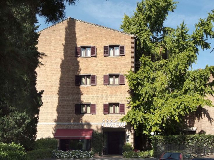 An hotel building surrounded by trees, featuring a simple and welcoming facade.