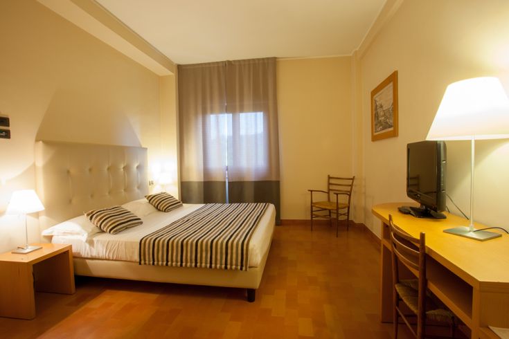 A comfortable hotel room with simple designed furniture and bright lighting.