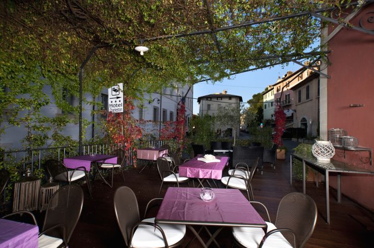 Simple outdoor area with tables and chairs, surrounded by greenery. Perfect for relaxing moments.