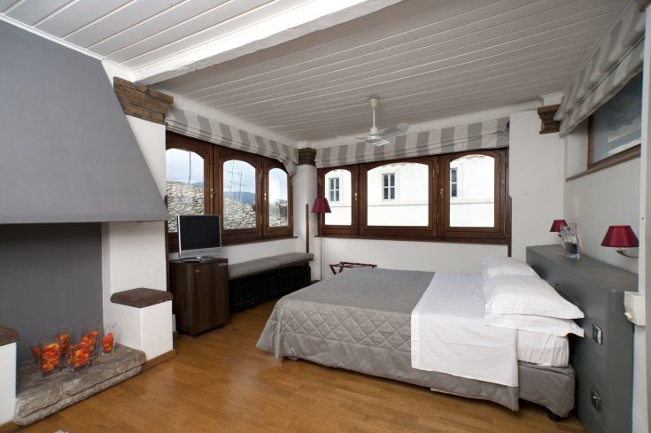 Cozy hotel room with simple furniture, featuring a relaxation area and wooden floors.