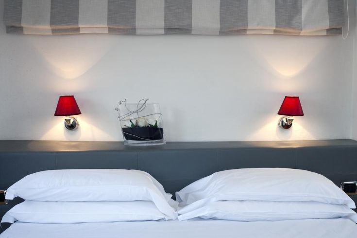 Simple hotel room with white beds and red lamps, perfect for a relaxing stay.