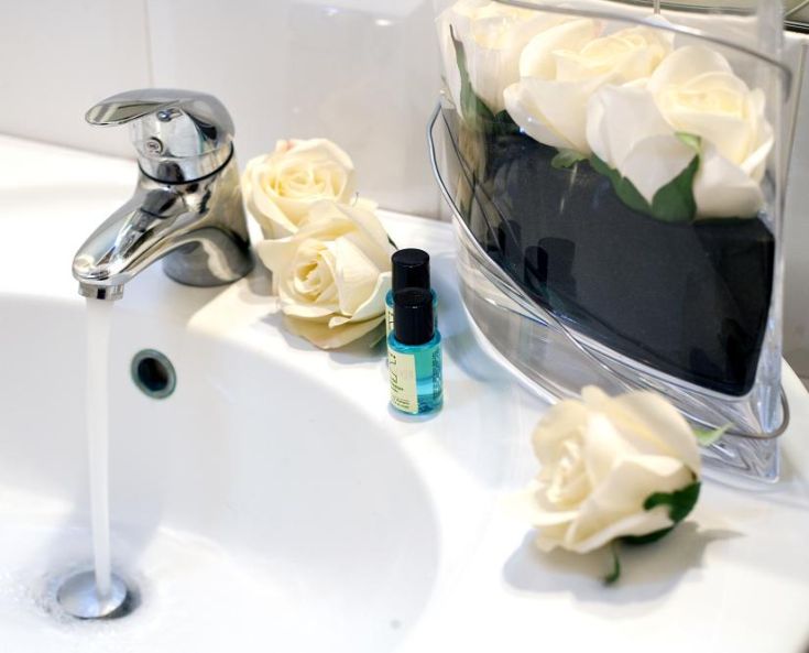 A simple sink adorned with white roses and various personal care products, depicting a moment of relaxation.
