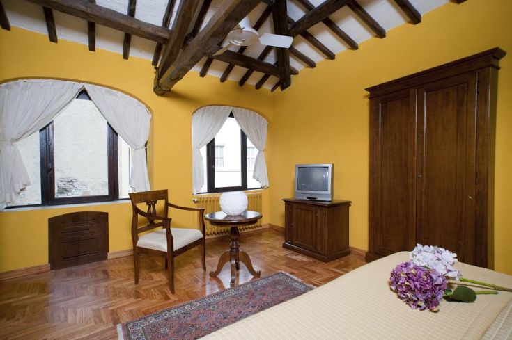 Simple room with yellow walls and exposed beams, vintage decor. Ideal for a comfortable stay.