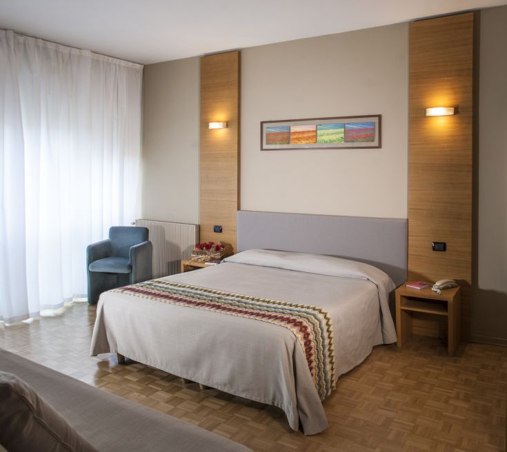 Camera di un hotel moderno, dotata di un letto matrimoniale e arredamento sobrio e funzionale.