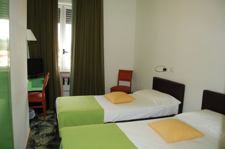Spacious hotel room with two single beds and a desk, perfect for a quiet and functional stay.