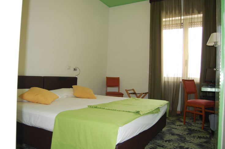 Well-lit and cozy hotel room with vibrant decorative elements and a view of a tranquil setting.