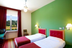 Spacious and comfortable hotel room with twin beds and a scenic view of the surrounding nature.