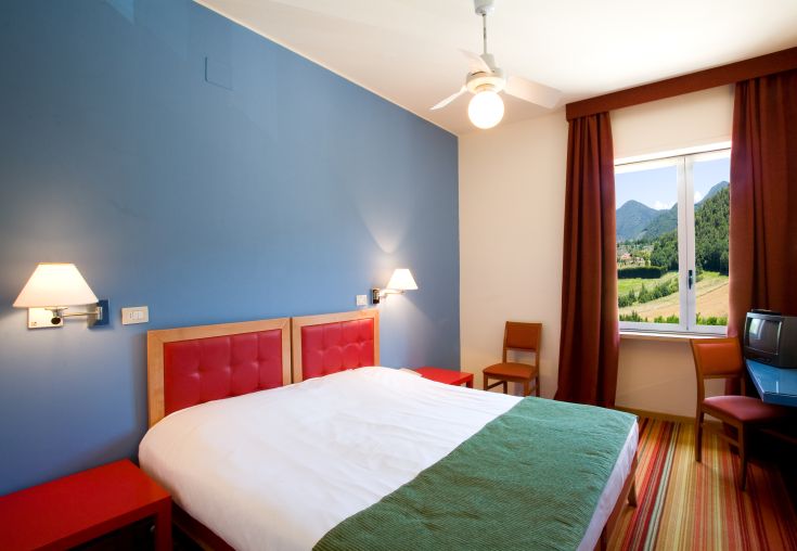 Simple and functional hotel room with a panoramic view of the hills, perfect for a peaceful stay.