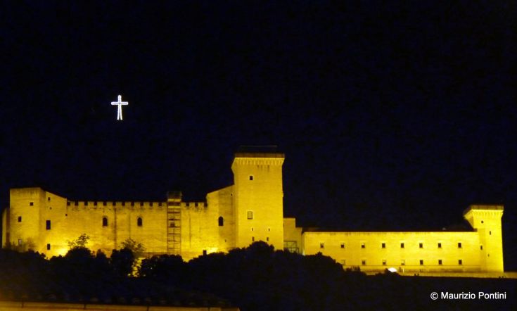 A historic building illuminated in the dark, with light reflecting off its walls.