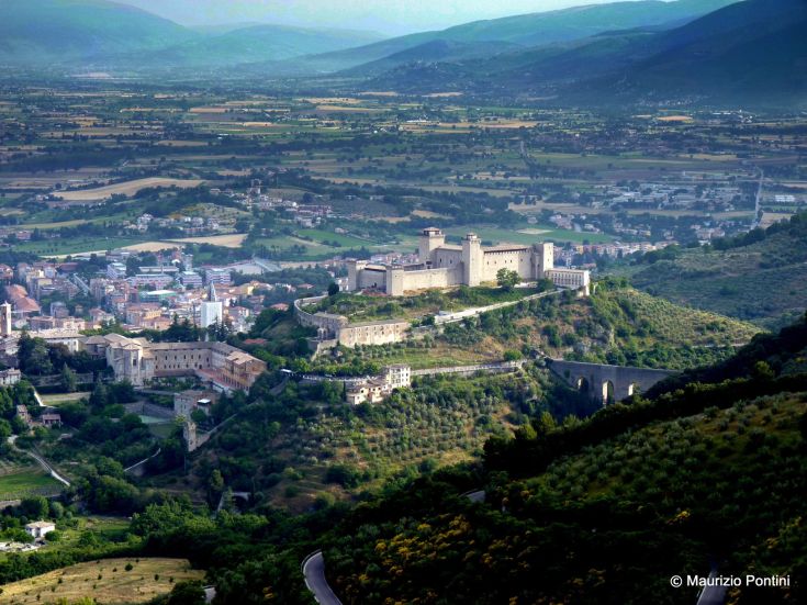 A scene of a castle set in a hilly landscape, featuring green meadows and cultivated fields.