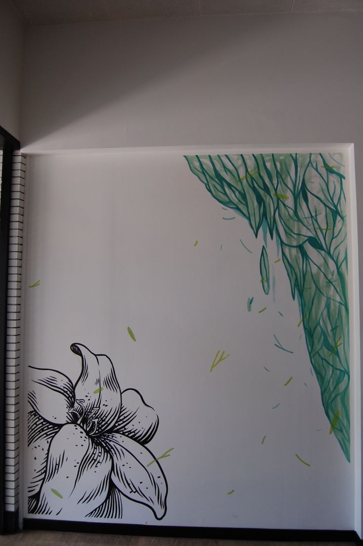 A mural featuring a stylized flower at the entrance of a building, highlighted by green hues.