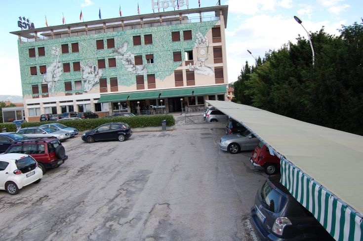 Exterior of Hotel Arca, a modern building with decorative murals and a parking area.
