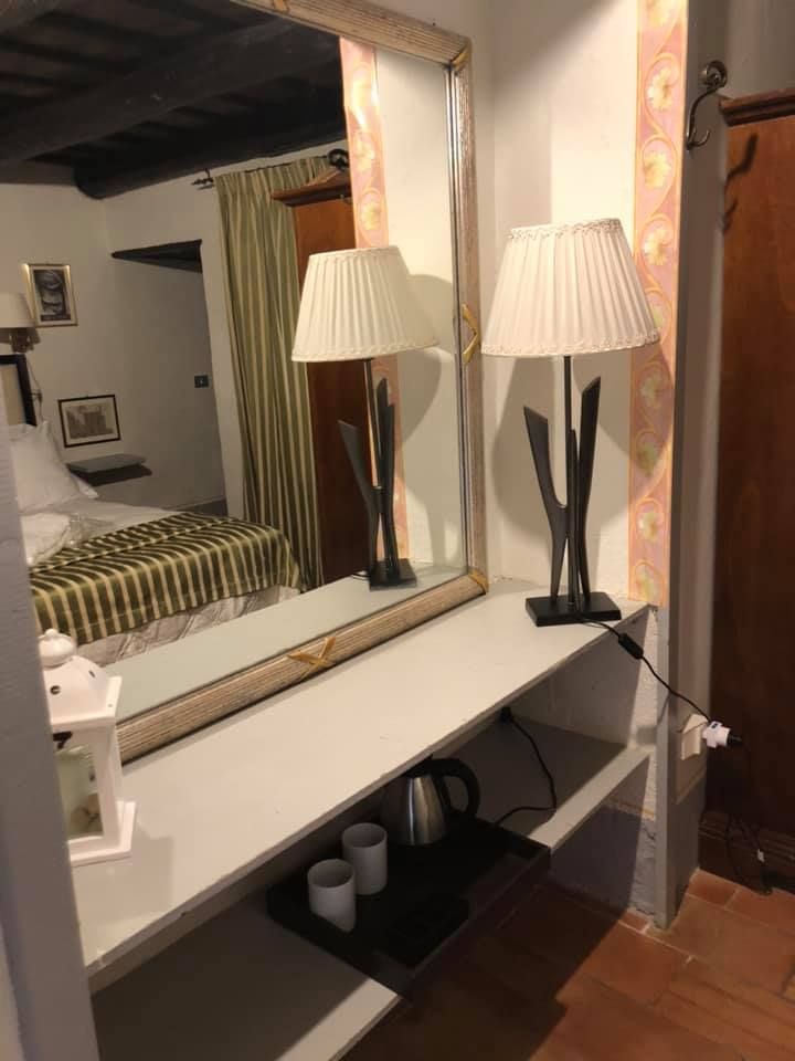 Un semplice angolo di una camera con lampada e uno specchio sulla parete.