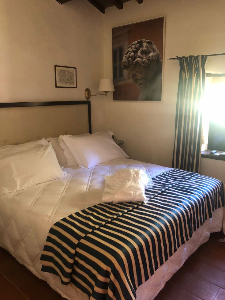 Camera semplice con un letto curato e alcune decorazioni sulle pareti.