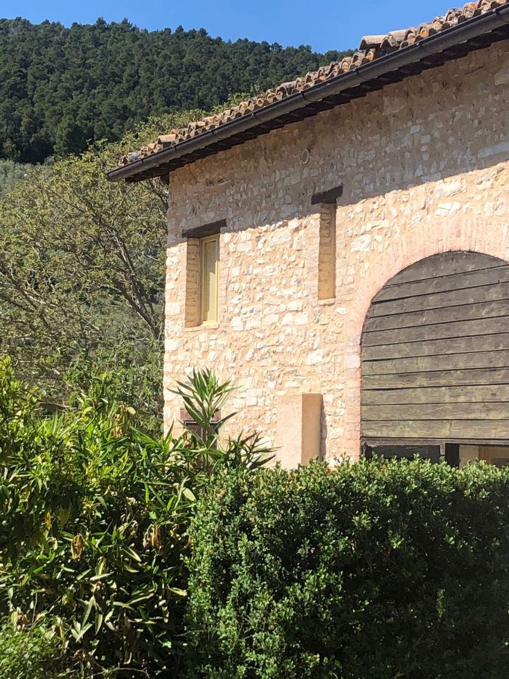 Un edificio in pietra circondato da alberi e vegetazione verde.