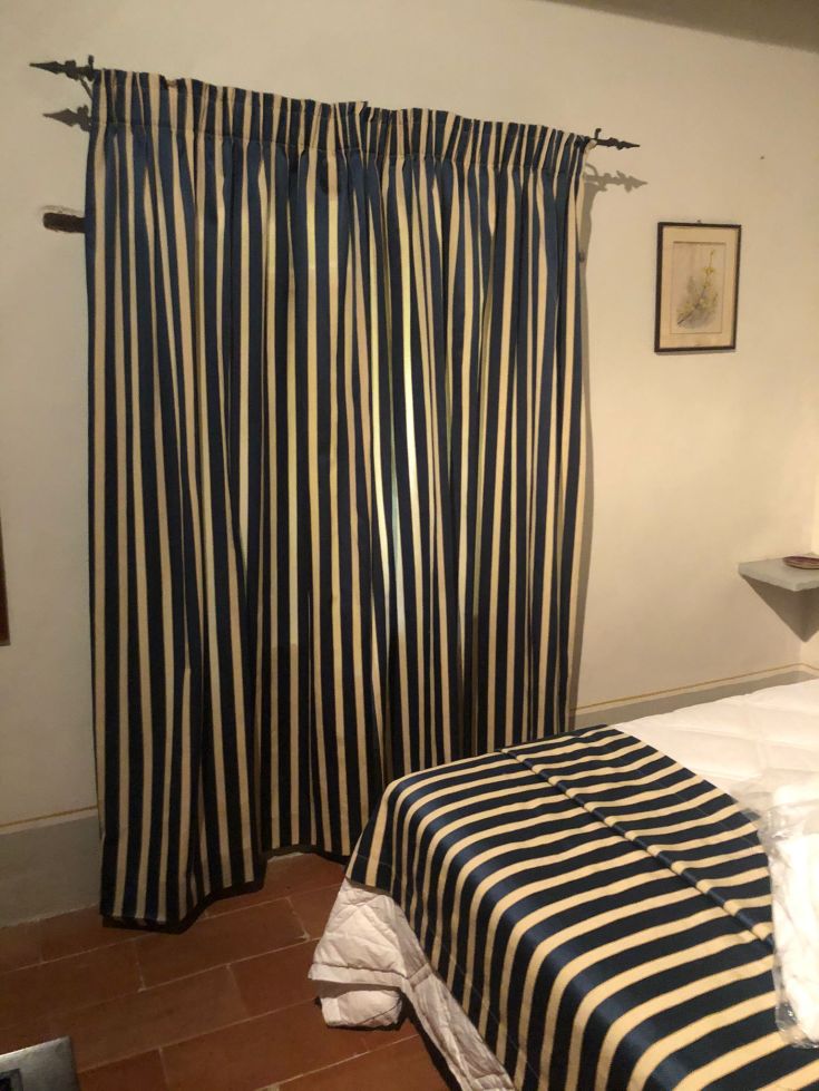 Tende a righe blu e beige adornano una camera da letto semplice e confortevole.