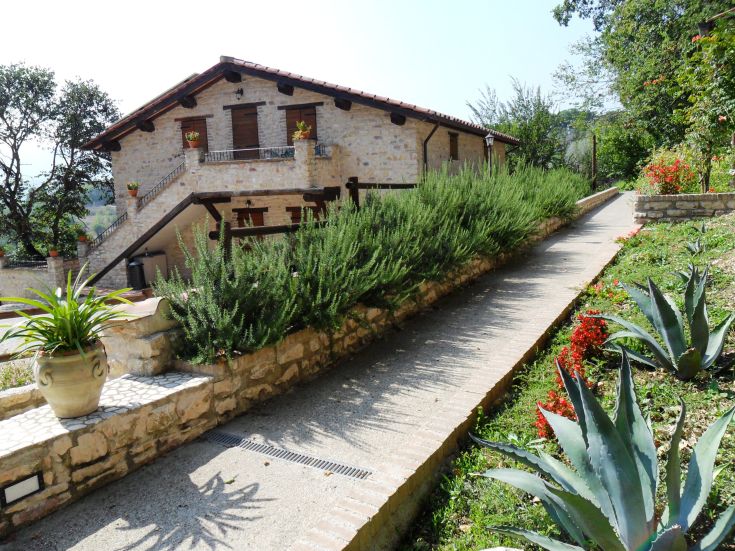 Ein Steingebäude, umgeben von Pflanzen, mit Blumen, die das umliegende Gebiet verschönern.