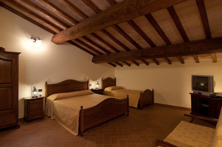 Geräumiges Zimmer mit Holzbalkendecke, Doppelbetten und Fernseher, ideal für entspannte Momente.