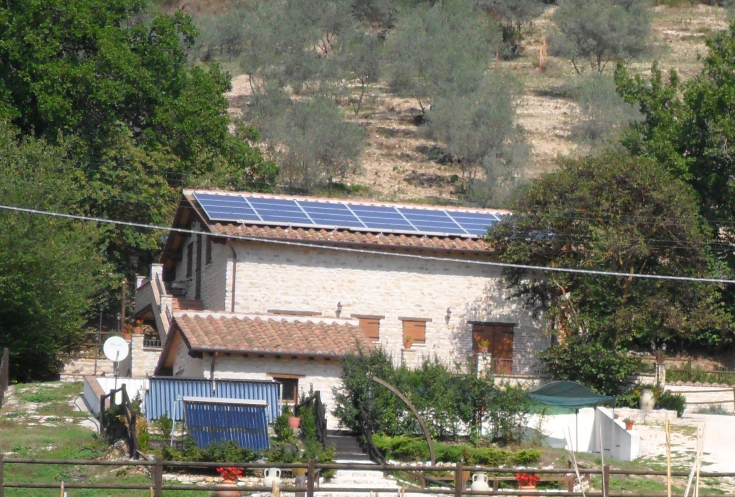 Ein Landhaus mit Solarpanelen, umgeben von typischer umbrischer Vegetation.
