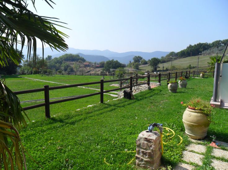 Ein gut gepflegter Garten mit großen Grünflächen und bunten Pflanzen, umgeben von Holzzäunen.