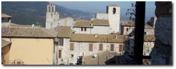 Scena tranquilla dei tetti di un borgo umbro, caratterizzato da antiche case in pietra e tetti in coppi.