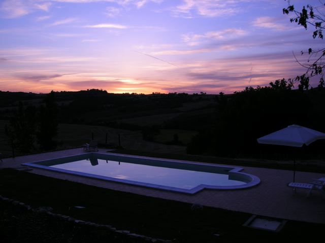 Sunset view from a farmhouse with a swimming pool in the Umbrian countryside.