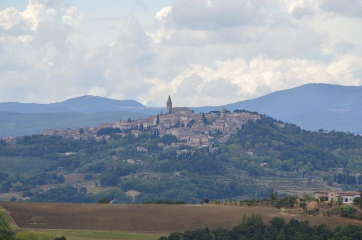 A peaceful view of an ancient city perched on a hill, surrounded by lush greenery.