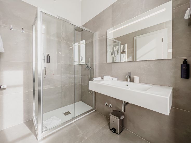 Salle de bain spacieuse et lumineuse avec douche pratique, lavabo simple et style moderne.