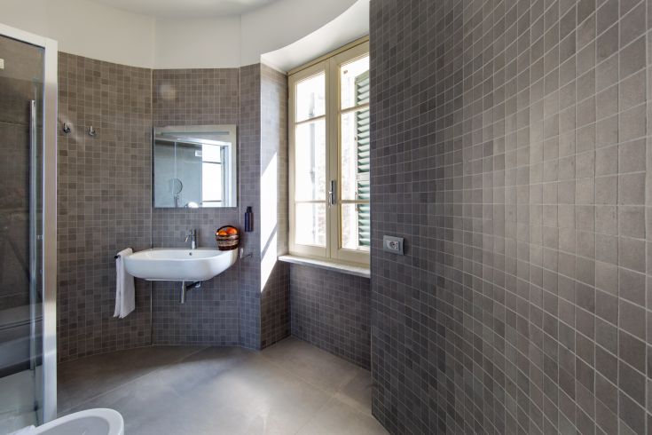 Salle de bains contemporaine avec des carreaux gris et une grande fenêtre, créant un espace lumineux et fonctionnel.