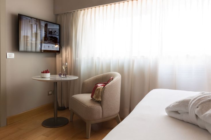 Un espace de détente confortable avec un fauteuil, une table basse et une télévision, éclairé par la lumière naturelle.