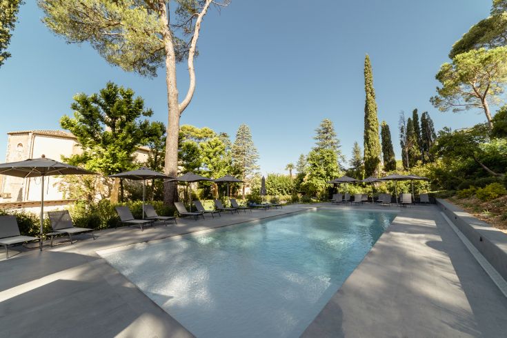 Une piscine située dans un parc, entourée d'arbres et d'équipements de détente.