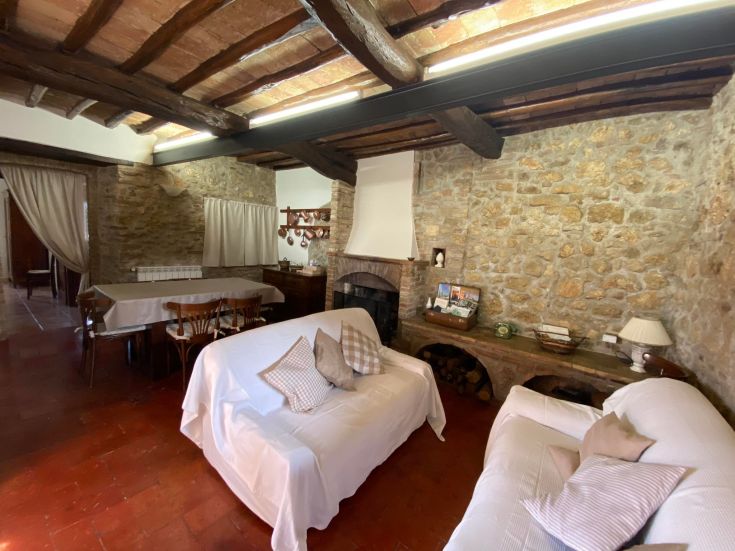 Ein rustikaler Wohnbereich im Agriturismus mit Steinmauern und freiliegenden Holzbohlen, einfach eingerichtet.