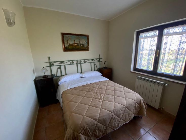 Ein einfacher Raum in einem Bauernhof mit Doppelbett und Blick auf die Landschaft.