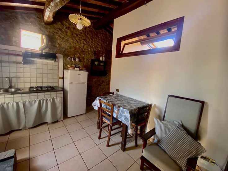 Gemütliche Küche in einem umbrischen Agriturismo, mit einfachen Möbeln und rustikalen Elementen, umgeben von Grün.