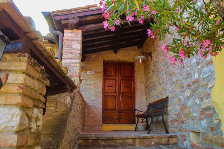 Zugang zum Bauernhof, der durch eine Anordnung von Blumen und eine Holzveranda gekennzeichnet ist.