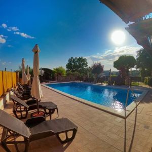 Ein Außenpool, umgeben von Liegen und Sonnenschirmen, eingebettet in eine natürliche Umgebung.