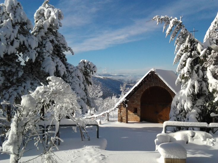 Un paysage d'hiver avec de la neige entourant une structure en bois accueillante.