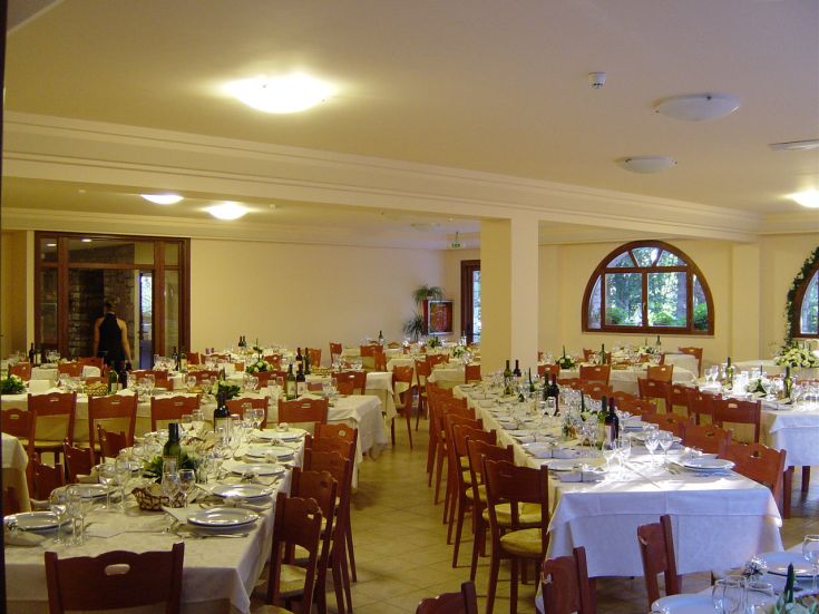 Salle à manger spacieuse avec des tables dressées et des bouteilles de vin, idéale pour des dîners et des rencontres.