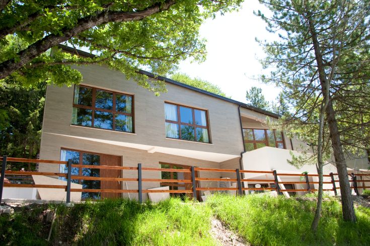 Bâtiment moderne situé dans un espace vert, entouré d'arbres et d'une grande pelouse.