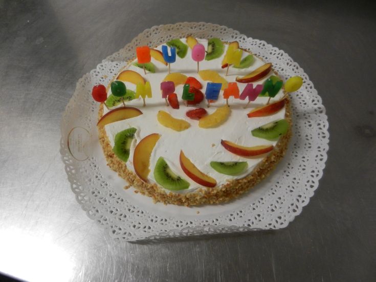 Torta colorata decorata con frutta fresca e candeline, ideale per celebrare un evento speciale.