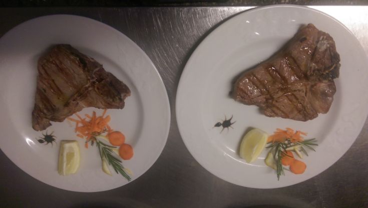 Due piatti di carne grigliata accompagnata da verdure e fette di limone.