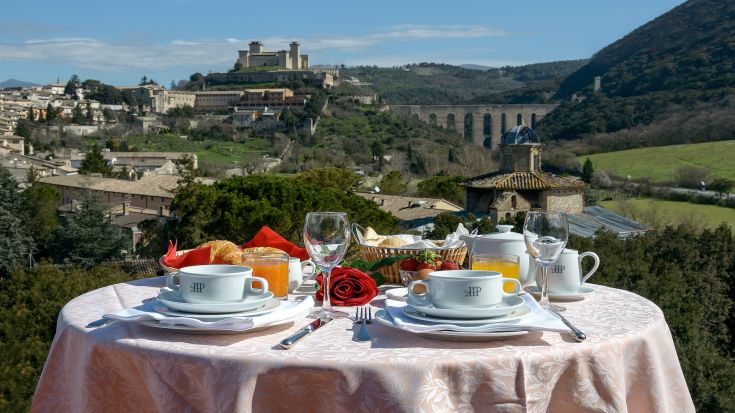Breakfast served in a hotel, overlooking the city of Spoleto and the surrounding greenery.