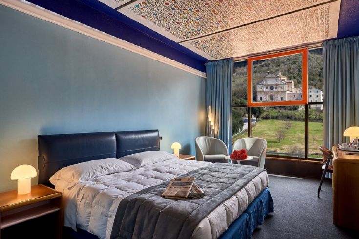 Spacious hotel room with a view of the Umbrian countryside, featuring simple decor and natural light.