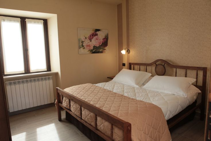 Camera semplice e luminosa con letti matrimoniali e dettagli floreali, adatta per un soggiorno tranquillo.